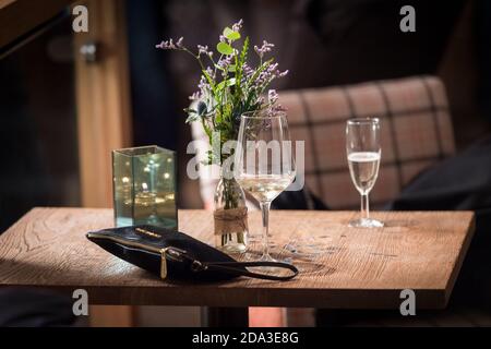 Bei einer Abendveranstaltung wurden Gläser Wein und eine Damenhandtasche auf einem Tisch zurückgelassen. Stockfoto