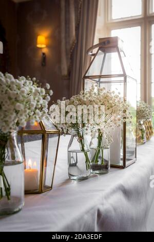 Blumen in Glasmilchflaschen auf einem Tisch bei einem Hochzeitsempfang. Stockfoto