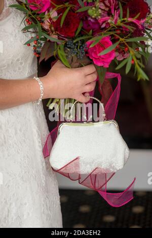 Nahaufnahme von Brautstrauß und Handtasche bei einem Hochzeitsempfang. Stockfoto
