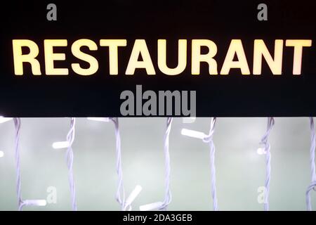 Blick auf glühendes Restaurant mit Inschrift auf schwarzem Hintergrund Stockfoto