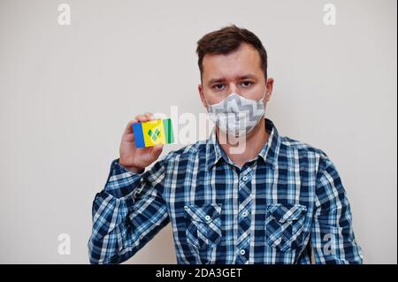 Mann im karierten Hemd zeigen St. Vincent und die Grenadinen Flagge Karte in der Hand, tragen Schutzmaske isoliert auf weißem Hintergrund. Amerikanische Länder Cor Stockfoto