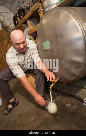 Ein Bauer gießt einen Krug hausgemachten Wein aus einem Bottich in seinem Keller im Kalaraci District, Moldawien. Stockfoto