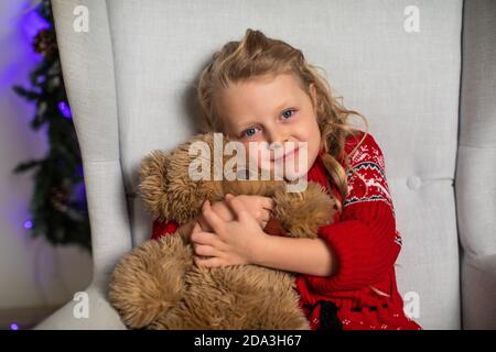 Mädchen Umarmungen Teddybär in roten Pullover für Weihnachten Stockfoto