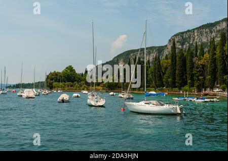 Wunderschöne Segelboote ruhen auf dem atemberaubenden blauen Wasser von Gardasee mit Bergen als Hintergrund und einem blauen Himmel an einem fabelhaften Frühlingstag Stockfoto