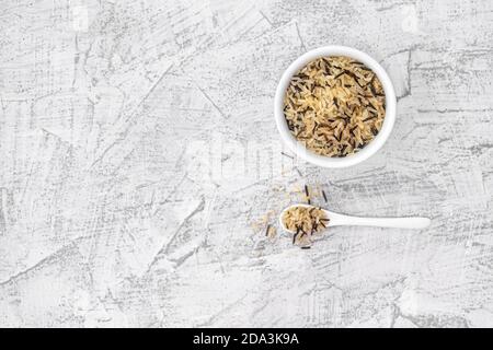 Gemischter Reis in weißem Teller und Löffel auf weißem Stein Hintergrund. Vegetarisches Superfood. Gemischte Reiskörner. Draufsicht mit Kopierbereich. Weißer und schwarzer Reis. Flach liegend. Stockfoto