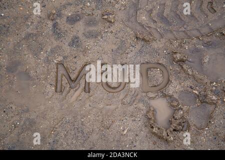 Das Wort Schlamm in nassen Schmutz Straßenoberfläche eingeprägt - Nahaufnahme mit selektivem Fokus Stockfoto