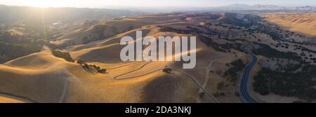 Goldenes Sonnenlicht scheint auf den sanften Hügeln in Nordkalifornien. Diese schönen, erodierten Hügel werden grün, sobald der Winter saisonalen Regen bringt. Stockfoto
