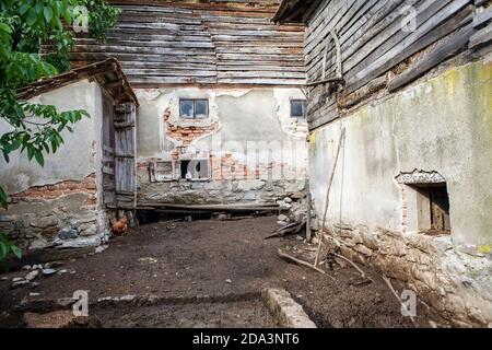 Hof in einem serbischen Balkan-Dorf mit ein paar Geflügel, eine Feldtoilette und eine Scheune voller Heu. Stockfoto