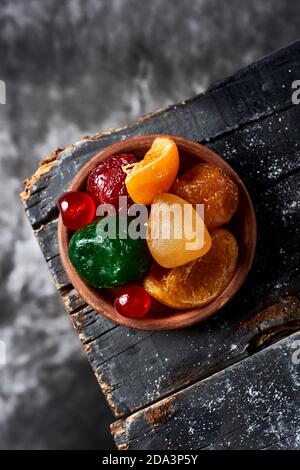 Blick aus der Vogelperspektive auf einige appetitliche spanische kandierte Früchte, wie Orange, Birne, Pflaume oder Maraschino Kirschen, in der Regel zu weihnachten gegessen, auf einem rustikalen Stockfoto