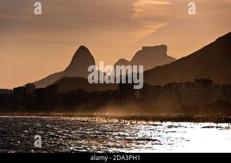 Landschaftlich schöner Blick auf den Sonnenuntergang am Copacabana Strand, Sonne geht hinter den Bergen, Rio de Janeiro, Brasilien Stockfoto