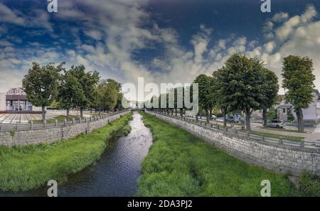 Schöne Aussicht von der Holzbrücke in der Stadt Knjazevac, Ostserbien. Promenade mit viel Gras, Bäumen und kleinen Timok Fluss im Sommer. Stockfoto