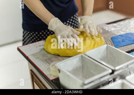 Weibliche Hände mit Handschuh Kürbisteig kneten. Stockfoto