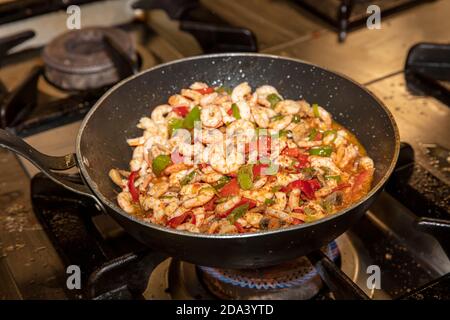 Garen Garnelen mit Austern mit Gemüse Tomaten und Grün und Mit Omelett auf einer Bratpfanne - auf einem Herd Mit Feuerhintergrund Stockfoto