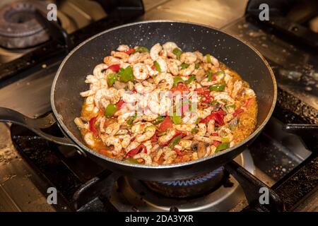 Garen Garnelen mit Austern mit Gemüse Tomaten und Grün und Mit Omelett auf einer Bratpfanne - auf einem Herd Mit Feuerhintergrund Stockfoto