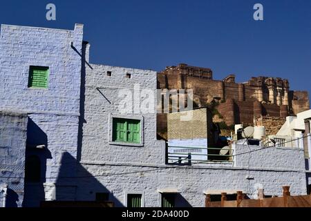 Blick auf Mehrangarh (Mehran Fort) von der alten Blauen Stadt. Ziegelmauer des alten Hauses auf einem Vordergrund. Jodhpur, Rajasthan, Indien Stockfoto