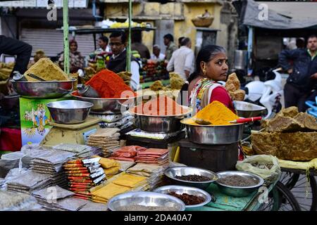 Udaipur, Rajasthan, Indien - Dezember 2016: Indische Frau verkauft bunte Gewürze (Curcuma, Curry, Chilipulver) auf dem traditionellen Straßenmarkt Stockfoto