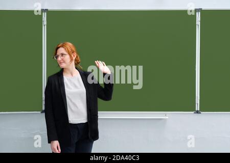 Schullehrer winkt mit der Hand gegen die Tafel, Raum kopieren. Das Konzept des Schulabscheidens, des Unterrichts oder der Entlassung Stockfoto