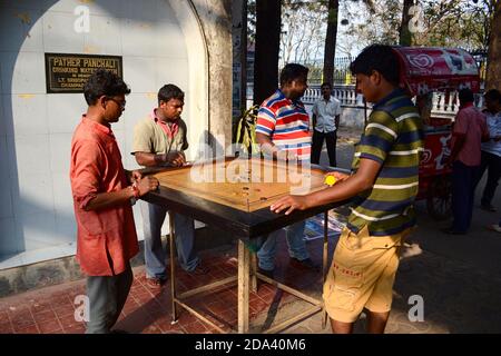 Kolkata, Indien - März, 2014: Indische Männer spielen Carrom-Spiel - traditionelle Tabletop-Spiel. Junge Erwachsene haben Spaß auf der Straße genießen Brettspiel ähnlich Stockfoto