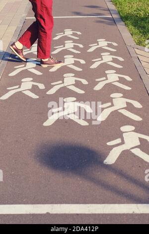 Frau überquert einen Radweg in einem Park an einem Fußgängerüberweg Stockfoto