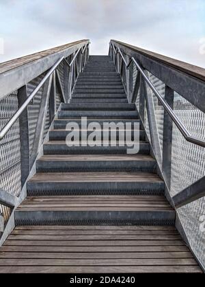 Treppen mit Edelstahlgeländer und Holztreppen. Treppe mit dem Himmel im Hintergrund. Treppen mit Stufen nach oben. Stockfoto