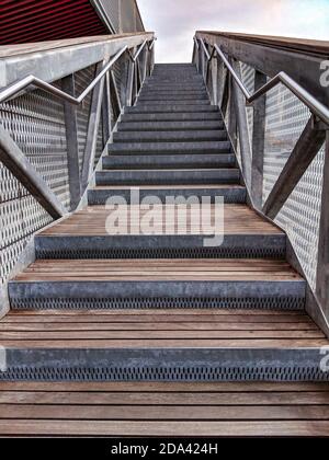 Treppen mit Edelstahlgeländer und Holztreppen. Treppe mit dem Himmel im Hintergrund. Treppen mit Stufen nach oben. Stockfoto