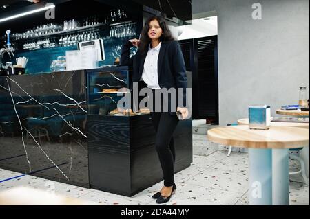 Wunderschöne indische Frau tragen formelle Posen im Café in der Nähe der Theke. Stockfoto