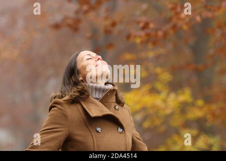 Frau mittleren Alters trägt braune Jacke atmen tiefe frische Luft In einem Wald im Herbst Stockfoto