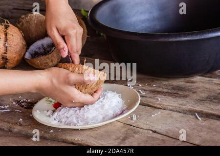 Weiche Fokus. Frau mit Hand kratzen Kokosnuss setzen den Behälter für Dessert und Essen zu machen Stockfoto