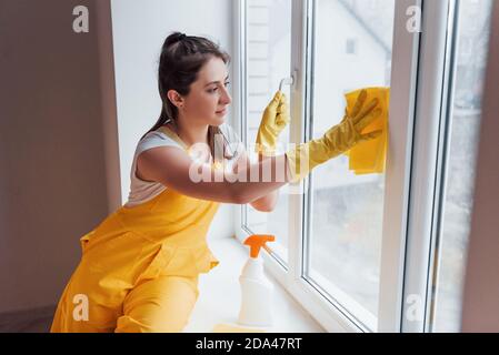 Hausfrau in gelb einheitliche Reinigung Fenster. Haus Renovierung Konzept Stockfoto