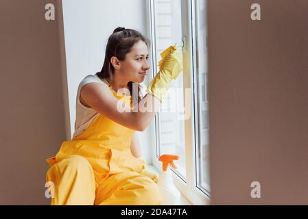 Hausfrau in gelb einheitliche Reinigung Fenster. Haus Renovierung Konzept Stockfoto