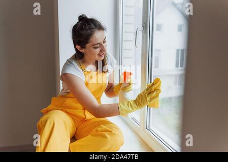 Hausfrau in gelb einheitliche Reinigung Fenster. Haus Renovierung Konzept Stockfoto