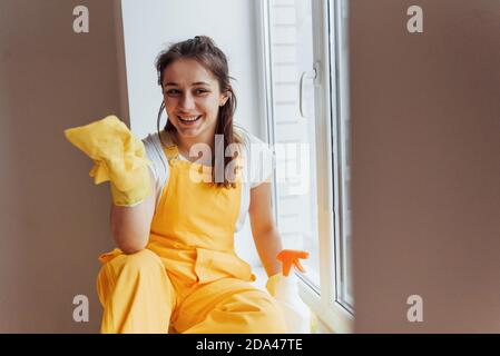 Hausfrau in gelb einheitliche Reinigung Fenster. Haus Renovierung Konzept Stockfoto