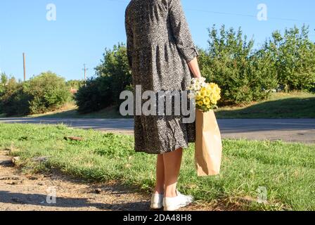 Ein Mädchen auf einem Spaziergang im Herbst Tag mit einem Handtüte mit schönen Blumen. Öko Tasche mit Chrysantheme Blumen. Stockfoto