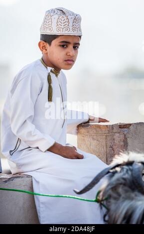 Nizwa, Oman, 2. Dezember 2016: Porträt eines einheimischen Jungen in traditioneller Kleidung auf dem Ziegenmarkt am Freitag in Nizwa, Oman Stockfoto