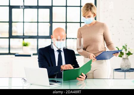 Eine Gruppe von Geschäftsleuten, die Gesichtsmaske tragen, während sie im Büro zusammenarbeiten. Geschäftstreffen. Stockfoto
