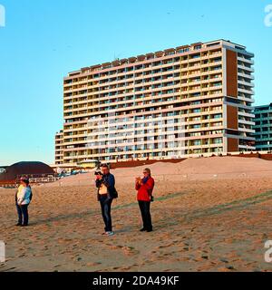 Sylt, 2. September 2020: Fotografen stehen an der Strandpromenade von Westerland vor einem großen hässlichen Wolkenkratzer und schauen auf den Sonnenuntergang Stockfoto