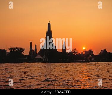 Thailand. Bangkok. Wat Arun Blick auf Tempelgebäude von der anderen Seite des Chao Phraya Flusses bei Sonnenuntergang. Stockfoto