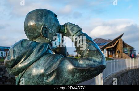 Lebensgroße Bronzeskulptur von Kenny Hunter genannt der Beobachter trägt eine Gesichtsmaske im Scottish Seabird Centre North Berwick, East Lothian, Schottland, Großbritannien Stockfoto