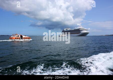 Kanalinseln. Guernsey. Kreuzfahrtschiff Ruby Princess vor Anker mit Schiffen Passagiershuttle und Trident Fähre von Herm. Stockfoto