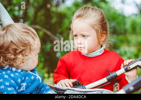 Schwester spielt mit ihrem Bruder im Kinderwagen Stockfoto