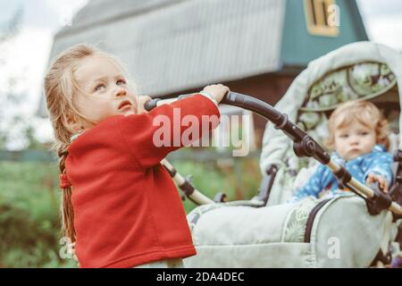 Schwester spielt mit ihrem Bruder im Kinderwagen Stockfoto