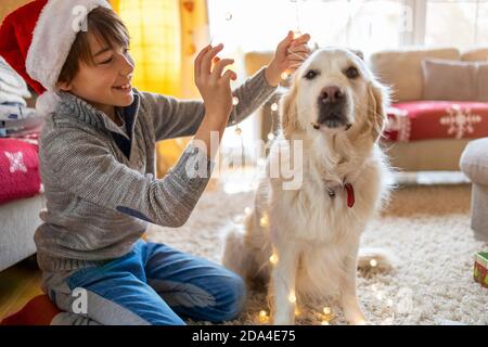 Junge und sein Hund genießen Weihnachten zusammen zu Hause Stockfoto