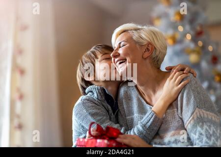 Lächelnder Junge, der zu Weihnachten ein Geschenk von seiner Mutter erhält Stockfoto