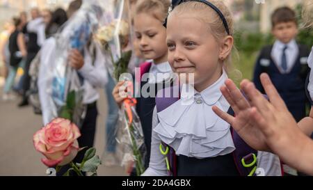 Schöne Mädchen gehen zur Schule mit Blumen. RUSSLAND, MOSKAU - SEP 01, 2020 Stockfoto