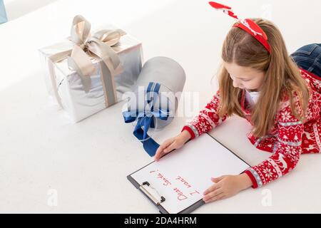 Liebe santa Brief von einem Kind zu Weihnachten geschrieben.Konzentriertes Kind ist in den Prozess des Denkens über alle ihre Wünsche und Wünsche beteiligt. Schön Stockfoto