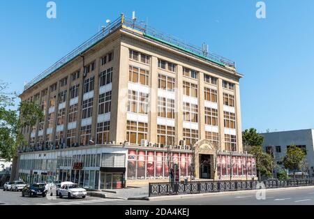 Baku, Aserbaidschan – 26. Juli 2020. Gebäude des zentralen Kaufhauses (Merkezi Univermaq, MOM) in Baku. Außenansicht mit Autos und Menschen, in su Stockfoto