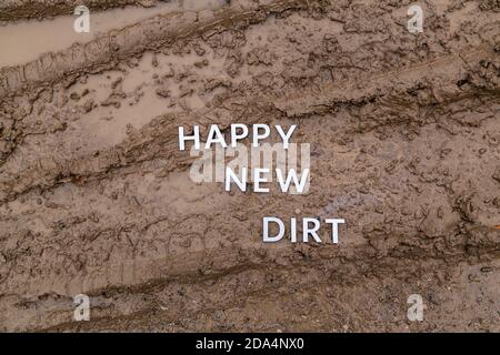 Die Worte glücklich neuen Schmutz gelegt mit silbernen Metall-Buchstaben Auf nasser Schlammoberfläche Stockfoto