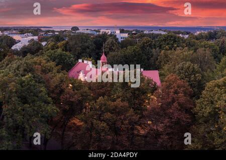 Altes Gebäude, umgeben von einem grünen Park. Abend Top-Ansicht der Nacht Tallinn, Estland. Dramatischer Sonnenuntergang Himmel Stockfoto