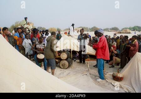 Mali, Westafrika, Sahara-Wüste, Essakane, Festival in der Wüste 2005. Informelle Trommelgruppe und ihre Zelte.Tuareg Kamelreiter im Hintergrund Stockfoto