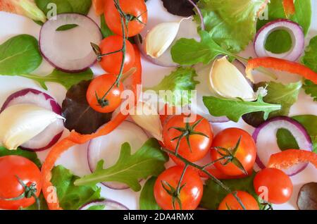 Bunte Salat Zutaten Muster aus Tomaten, Ruccola, lila Zwiebelringe, rote Paprika, Chili, Knoblauch, Gurkenscheiben und Basilikum auf weiß Stockfoto